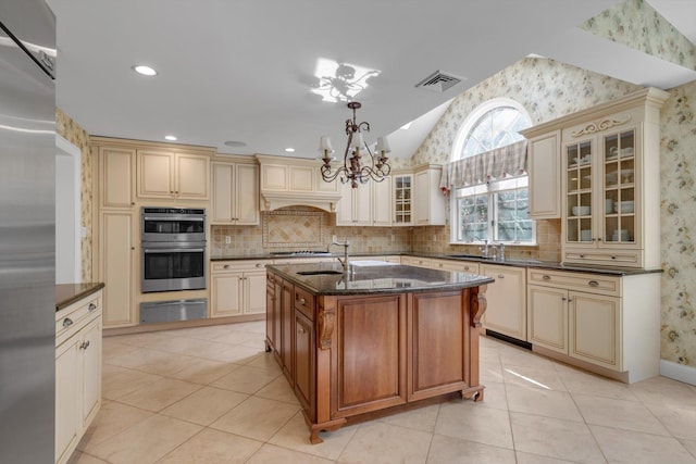 kitchen with cream cabinets, a warming drawer, a chandelier, dark stone counters, and lofted ceiling