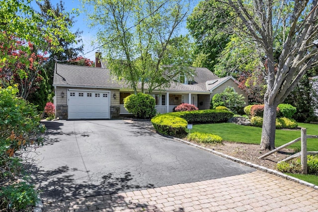 view of front of house with asphalt driveway, a garage, a front lawn, and stone siding