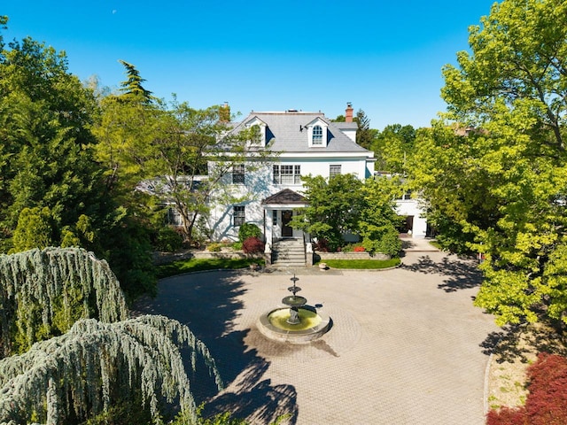 view of front of property with a chimney and curved driveway