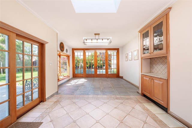 doorway featuring french doors, baseboards, and a skylight