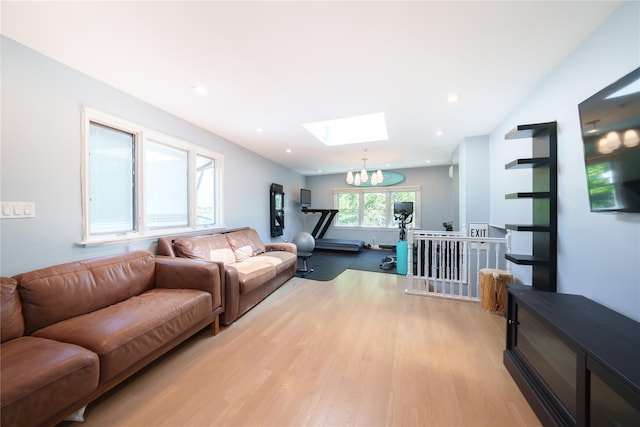 living area featuring a skylight, light wood-style floors, a chandelier, and recessed lighting