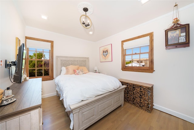 bedroom with baseboards, light wood-type flooring, and ornamental molding
