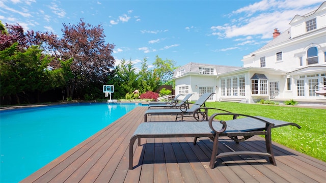 wooden terrace with an outdoor pool and a lawn