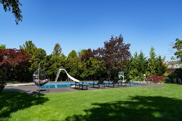 outdoor pool with a water slide and a yard