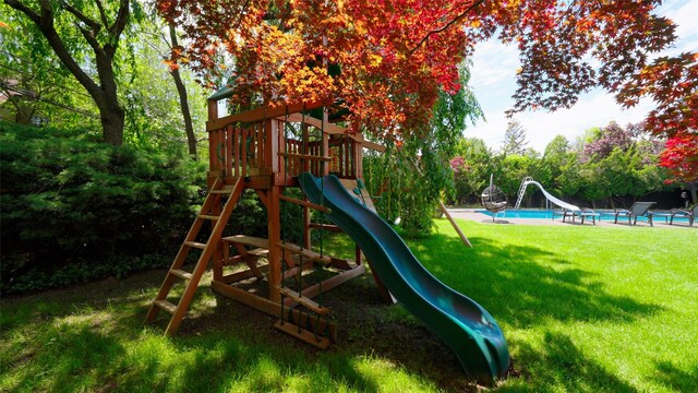 community playground with an outdoor pool, a yard, and view of scattered trees