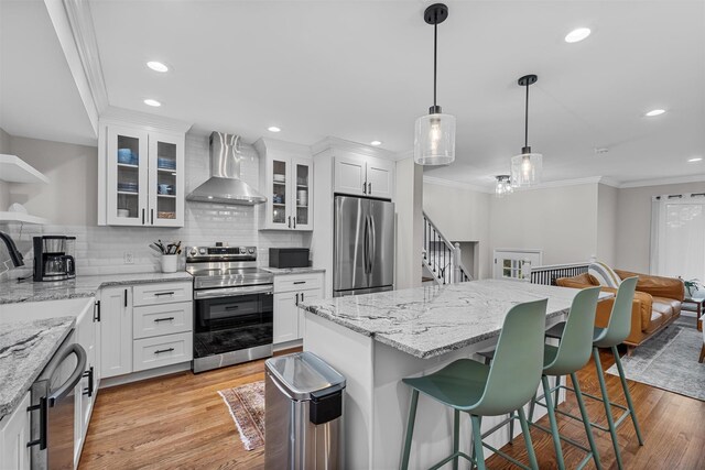 112 Edgehill Dr, Wappingers Falls, NY 12590 - kitchen with stainless steel appliances, wall chimney range hood, ornamental molding, backsplash, and a breakfast bar