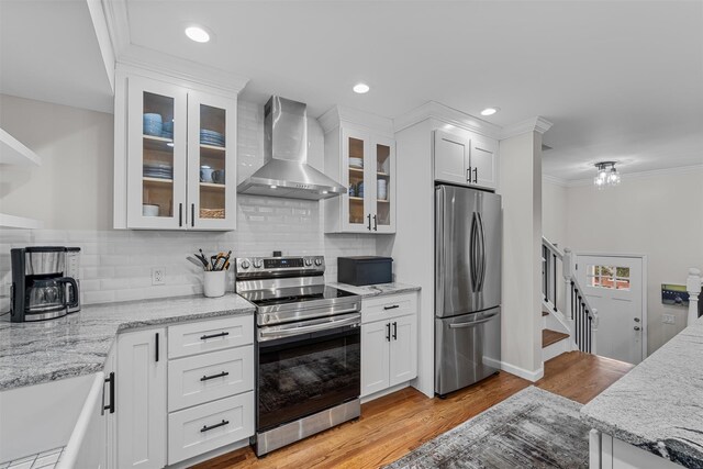 112 Edgehill Dr, Wappingers Falls, NY 12590 - kitchen featuring stainless steel appliances, wall chimney range hood, white cabinetry, light wood-type flooring, and crown molding