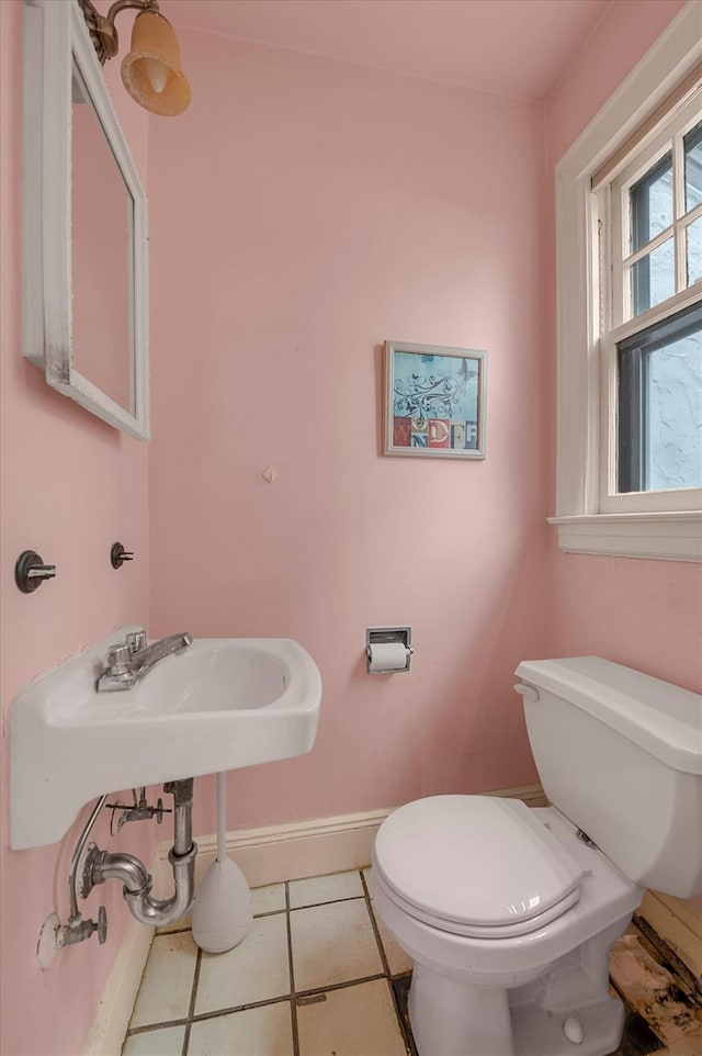 bathroom with toilet, baseboards, and tile patterned flooring