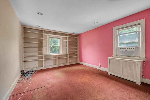 carpeted spare room with radiator heating unit, cooling unit, baseboards, built in shelves, and recessed lighting