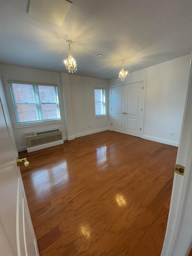 42-23 212th St Unit 3C, Bayside, NY 11361 - empty room with a chandelier, a wall mounted AC, wood finished floors, and baseboards