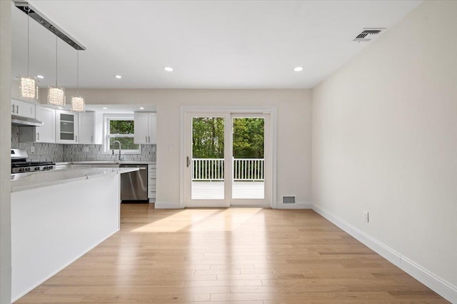 8 April Ave, Dix Hills, NY 11746 - kitchen featuring appliances with stainless steel finishes, light countertops, light wood finished floors, glass insert cabinets, and recessed lighting