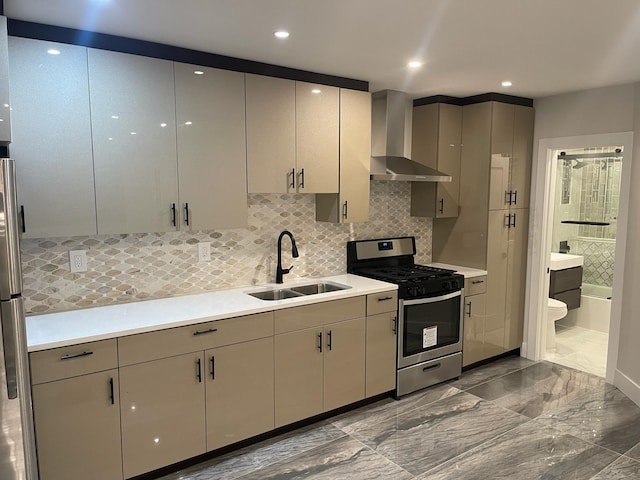 kitchen featuring appliances with stainless steel finishes, wall chimney range hood, a sink, gray cabinets, and dark marble finish flooring