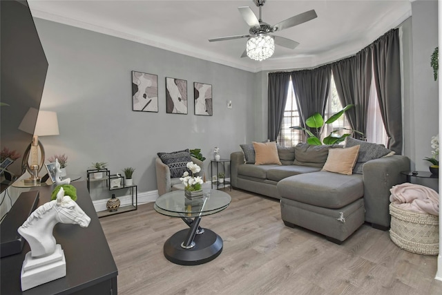 living area featuring wood finished floors, a ceiling fan, crown molding, and baseboards