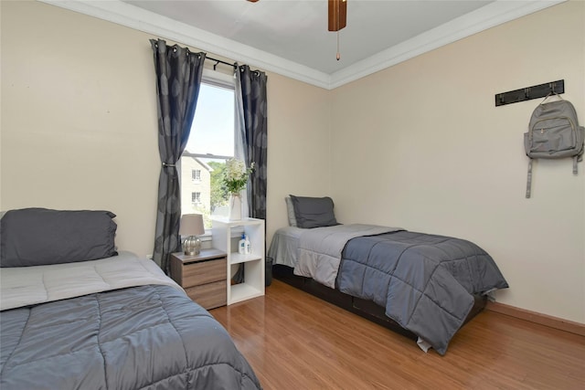 bedroom with wood finished floors, ornamental molding, and ceiling fan