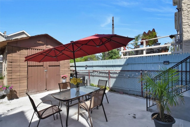 view of patio featuring a fenced backyard, a storage shed, outdoor dining area, and an outbuilding