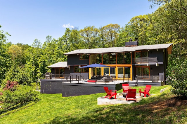 back of house with a lawn, a balcony, a chimney, and a patio