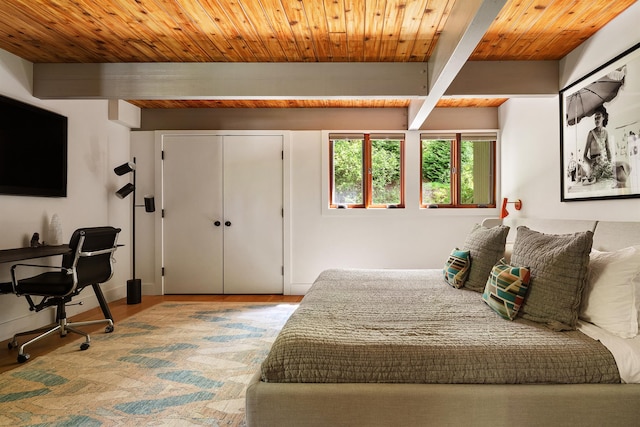bedroom with beam ceiling, wood finished floors, wooden ceiling, and a closet