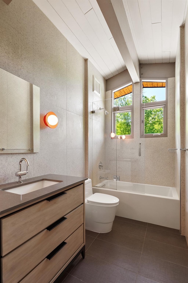 bathroom with toilet, washtub / shower combination, vanity, tile walls, and tile patterned floors