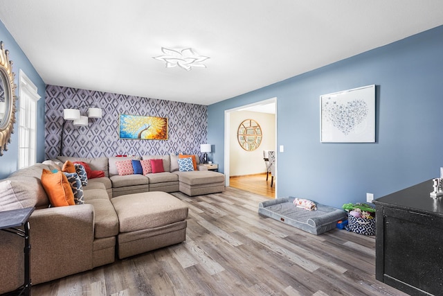 living area with an accent wall, wallpapered walls, and wood finished floors