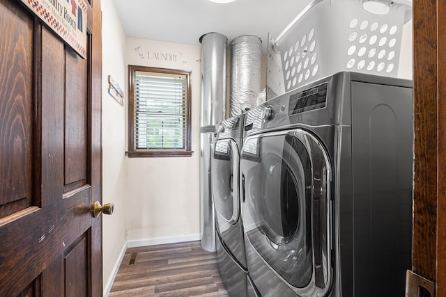 clothes washing area featuring washer and clothes dryer, baseboards, and wood finished floors