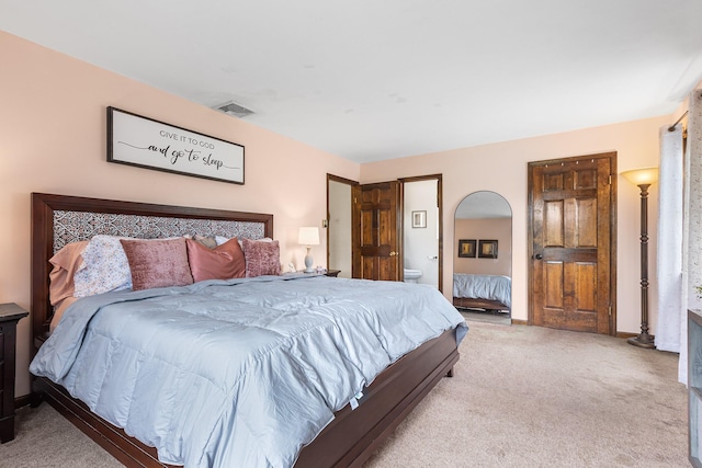 bedroom with light colored carpet, ensuite bathroom, and baseboards