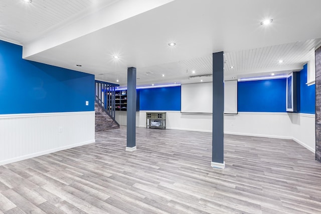 finished basement with a wainscoted wall and wood finished floors