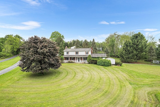 view of green lawn with a storage unit, an outbuilding, and covered porch