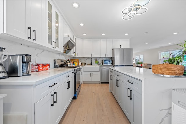 3875 S St, Seaford, NY 11783 - kitchen with stainless steel appliances, a sink, wall chimney exhaust hood, white cabinets, and recessed lighting