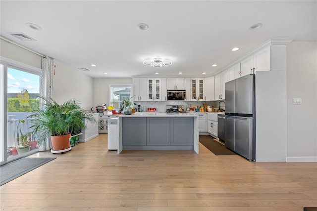 3875 S St, Seaford, NY 11783 - kitchen featuring appliances with stainless steel finishes, white cabinets, light countertops, light wood-style flooring, and recessed lighting
