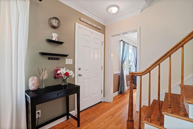 foyer with crown molding, light wood-style flooring, and stairs