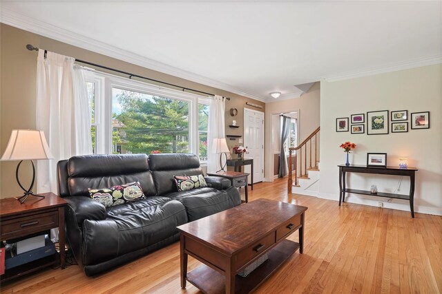 living area featuring light wood-style floors, ornamental molding, stairs, and baseboards