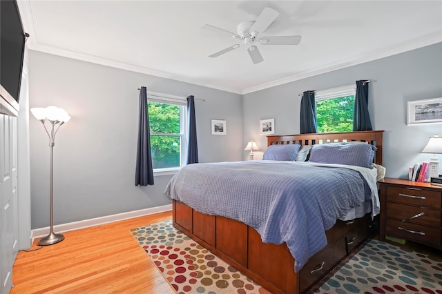 bedroom featuring multiple windows, wood finished floors, crown molding, baseboards, and ceiling fan