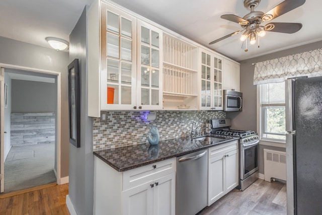 251-12 71st Rd Unit 29B, Bellerose, NY 11426 - kitchen featuring stainless steel appliances, radiator heating unit, a sink, light wood-style floors, and decorative backsplash