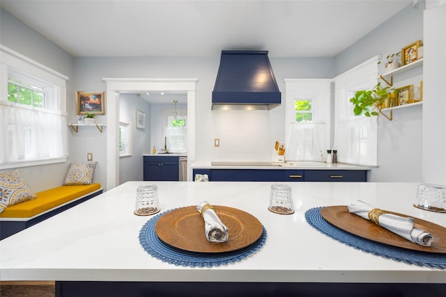 kitchen with blue cabinetry, custom range hood, light countertops, electric stovetop, and a sink