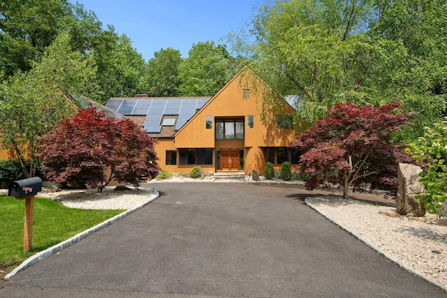 5 Ponds Ln, Purchase, NY 10577 - view of front facade with roof mounted solar panels and asphalt driveway