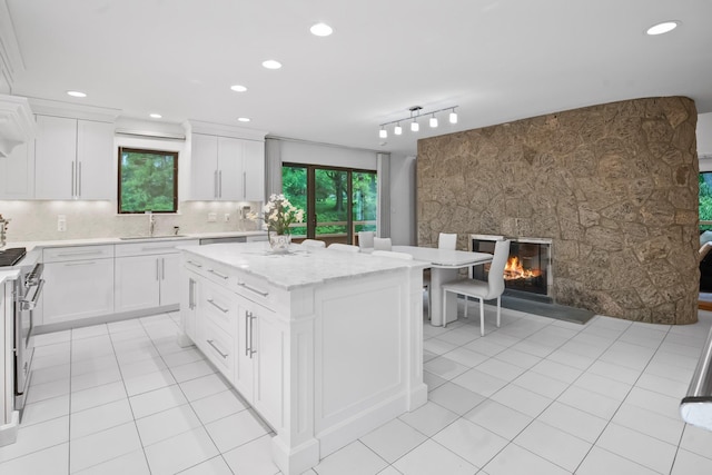 5 Ponds Ln, Purchase, NY 10577 - kitchen featuring a center island, high end stove, light tile patterned flooring, white cabinetry, and recessed lighting