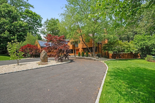 5 Ponds Ln, Purchase, NY 10577 - obstructed view of property featuring a front yard, roof mounted solar panels, and stucco siding
