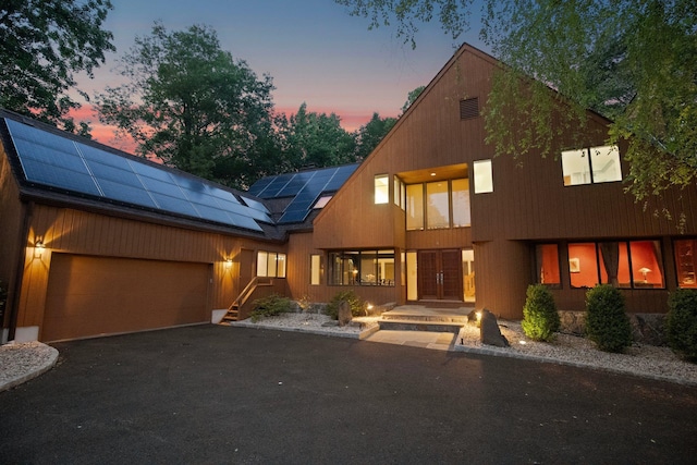 5 Ponds Ln, Purchase, NY 10577 - view of front of house with roof mounted solar panels, a garage, and driveway