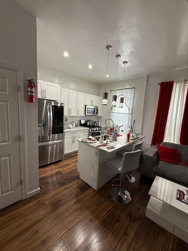 1956 Anthony Ave, Bronx, NY 10457 - kitchen featuring stainless steel appliances, white cabinets, decorative backsplash, a breakfast bar area, and dark wood-type flooring
