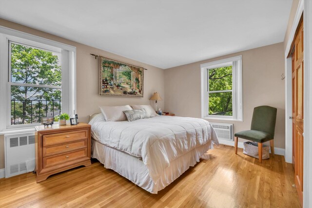209-25 18th Ave Unit 3J, Bayside, NY 11360 - bedroom with radiator, light wood-style flooring, an AC wall unit, and baseboards