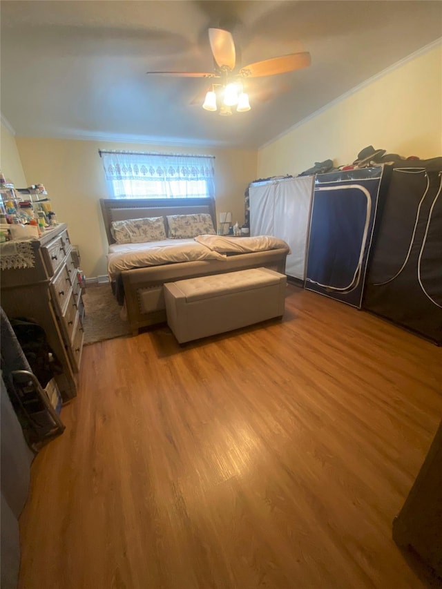 bedroom with wood finished floors, a ceiling fan, and ornamental molding