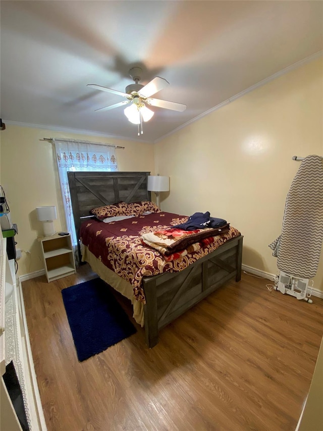 bedroom featuring wood finished floors, ornamental molding, a ceiling fan, and baseboards