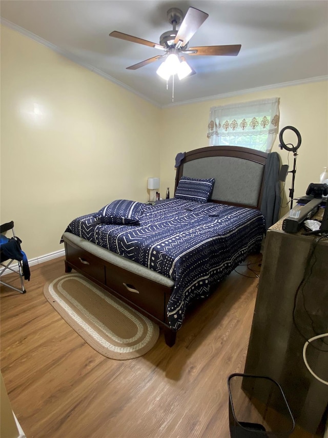 bedroom with ornamental molding, wood finished floors, ceiling fan, and baseboards
