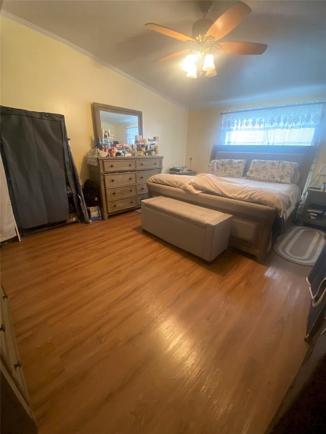 bedroom featuring light wood finished floors, ornamental molding, and a ceiling fan