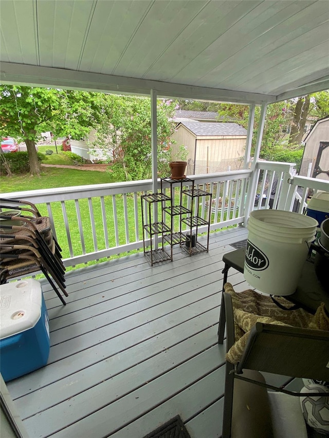 wooden terrace featuring a storage shed, an outdoor structure, and a lawn