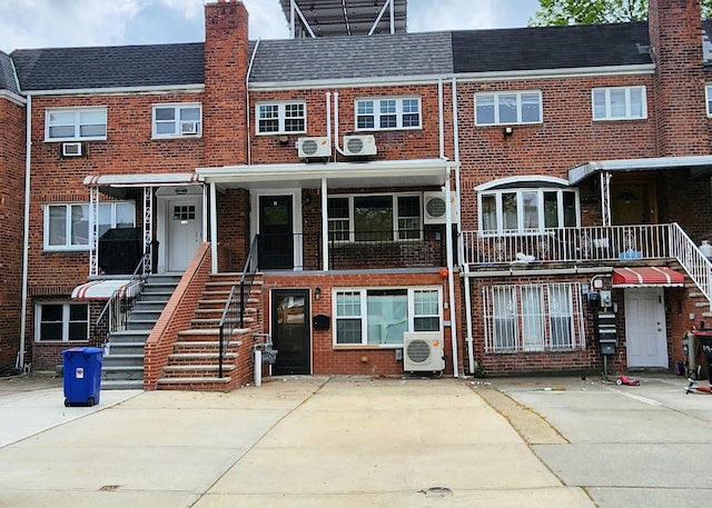 view of front of house featuring brick siding, ac unit, and a chimney