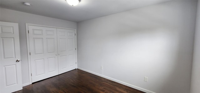 unfurnished bedroom featuring a closet, baseboards, and dark wood-style floors