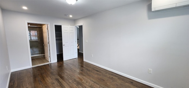 unfurnished bedroom with an AC wall unit, baseboards, dark wood-type flooring, recessed lighting, and a closet