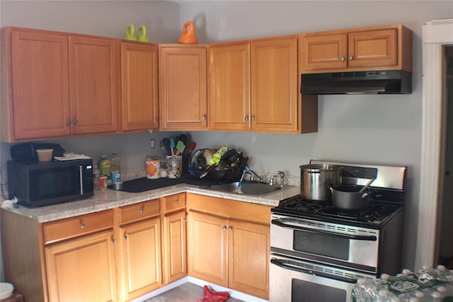 164 Winnikee Ave, Poughkeepsie, NY 12601 - kitchen with stainless steel range with gas cooktop, black microwave, a sink, under cabinet range hood, and light stone counters