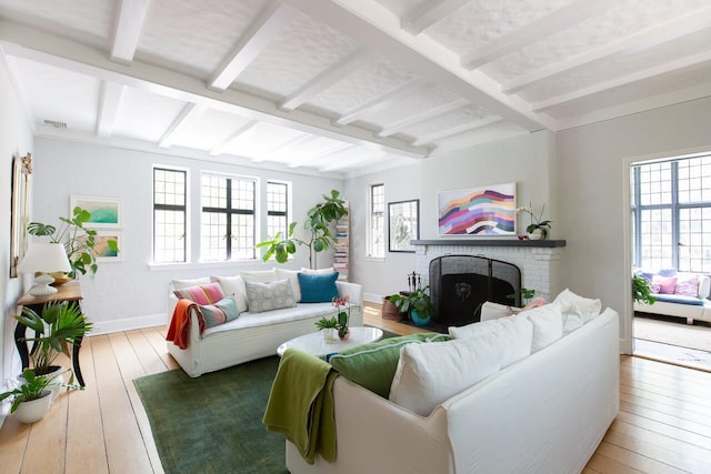 living room featuring beam ceiling, baseboards, a brick fireplace, and wood-type flooring